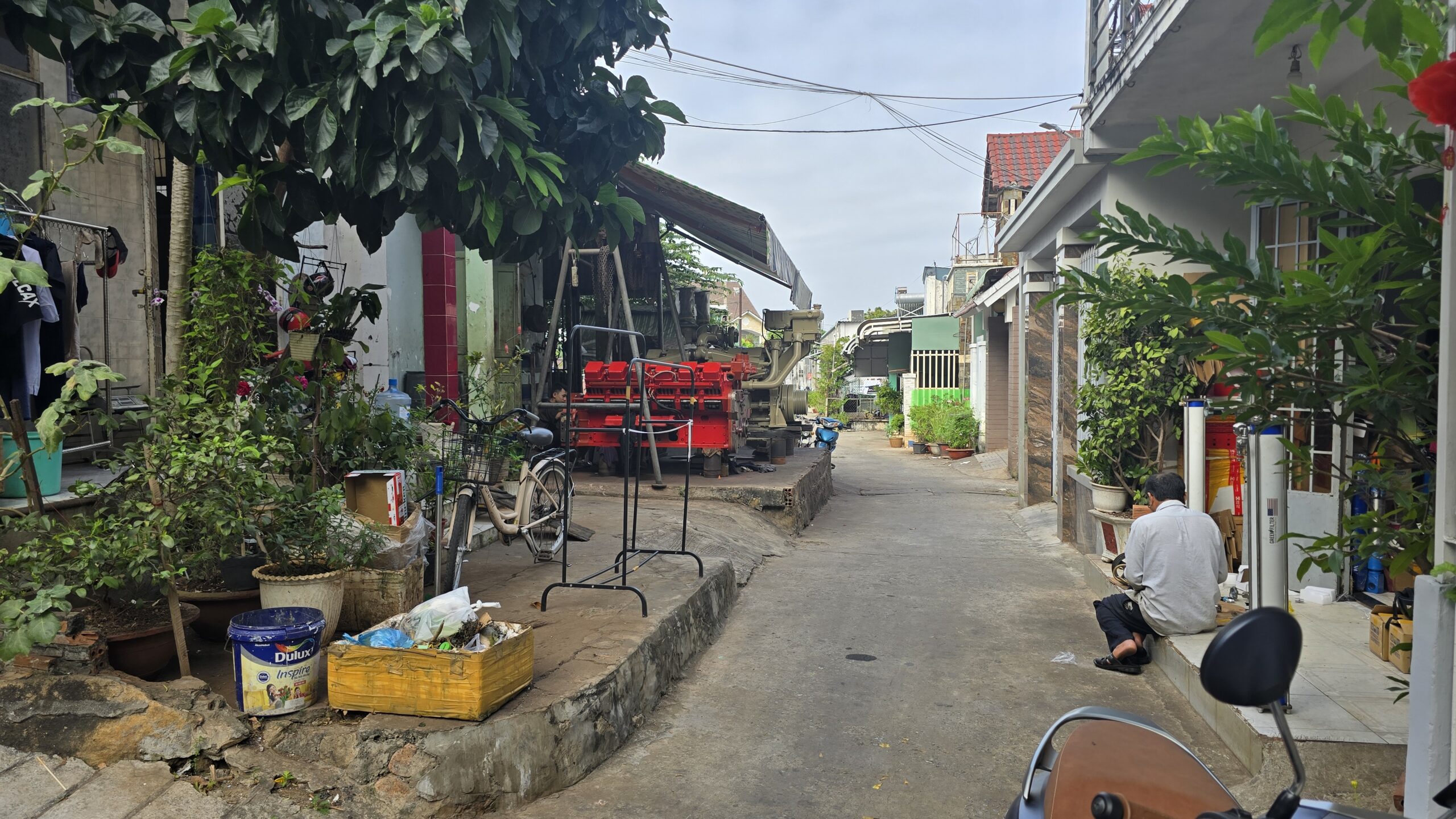 Het straatje waar de familie van Nhi woont, met op de achtergrond een werkplaats voor grote dieselmotoren.